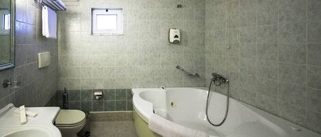 A bathroom with a bathtub, toilet, sink, and a small window.
