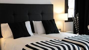 Een hotelkamer met een groot bed, een zwart-wit gestreept beddekleed en een zwart bekleed hoofdeinde.