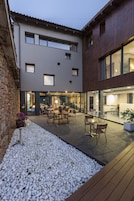 Un edificio moderno con un patio amoblado con mobiliario exterior y una pared de piedra.