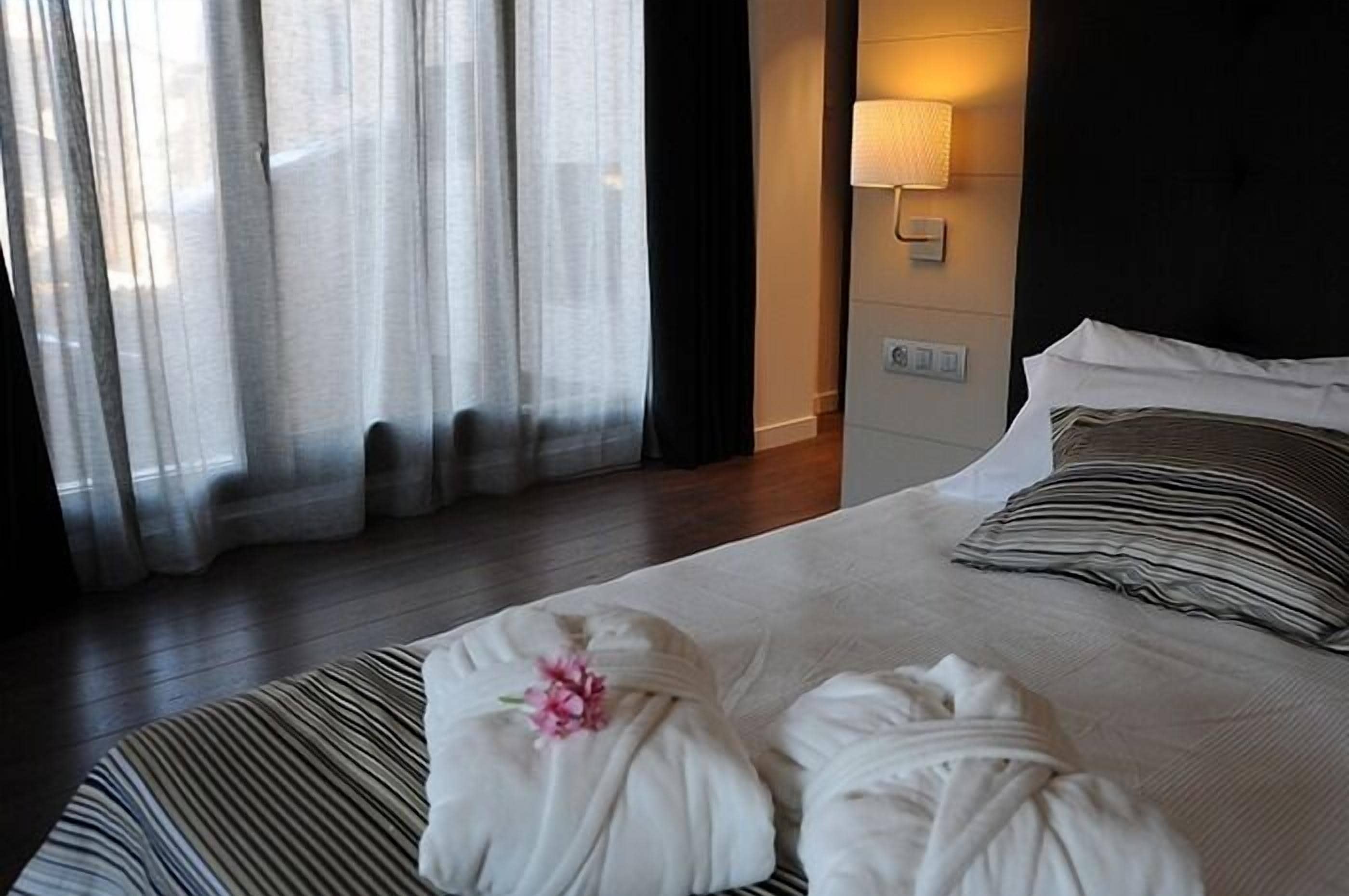 Ein Hotelzimmer mit einem Bett, einer Nachttischlampe und durchsichtigen Vorhängen.