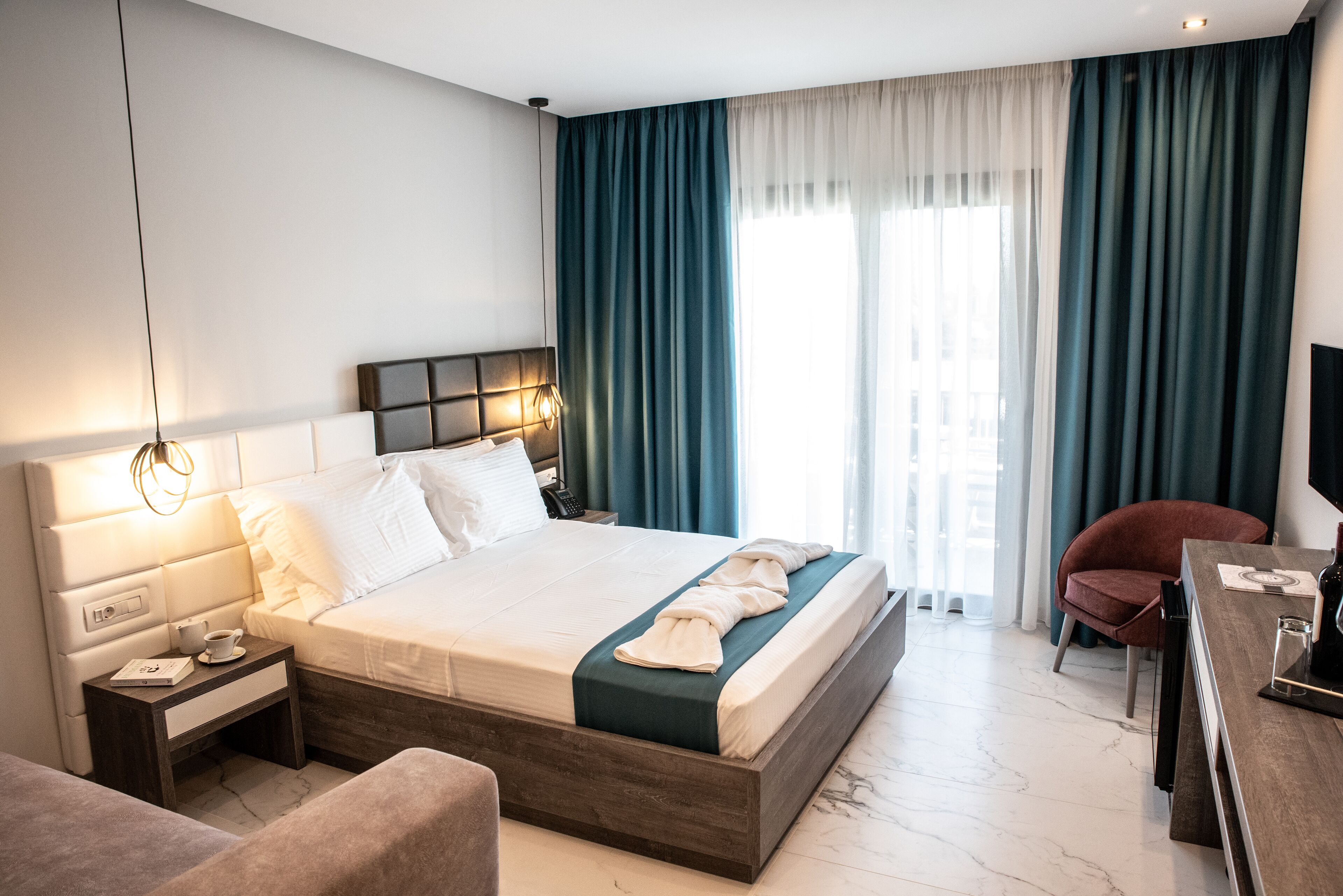 Una habitación de hotel moderna con una cama grande, una mesita de noche y un escritorio con una silla.