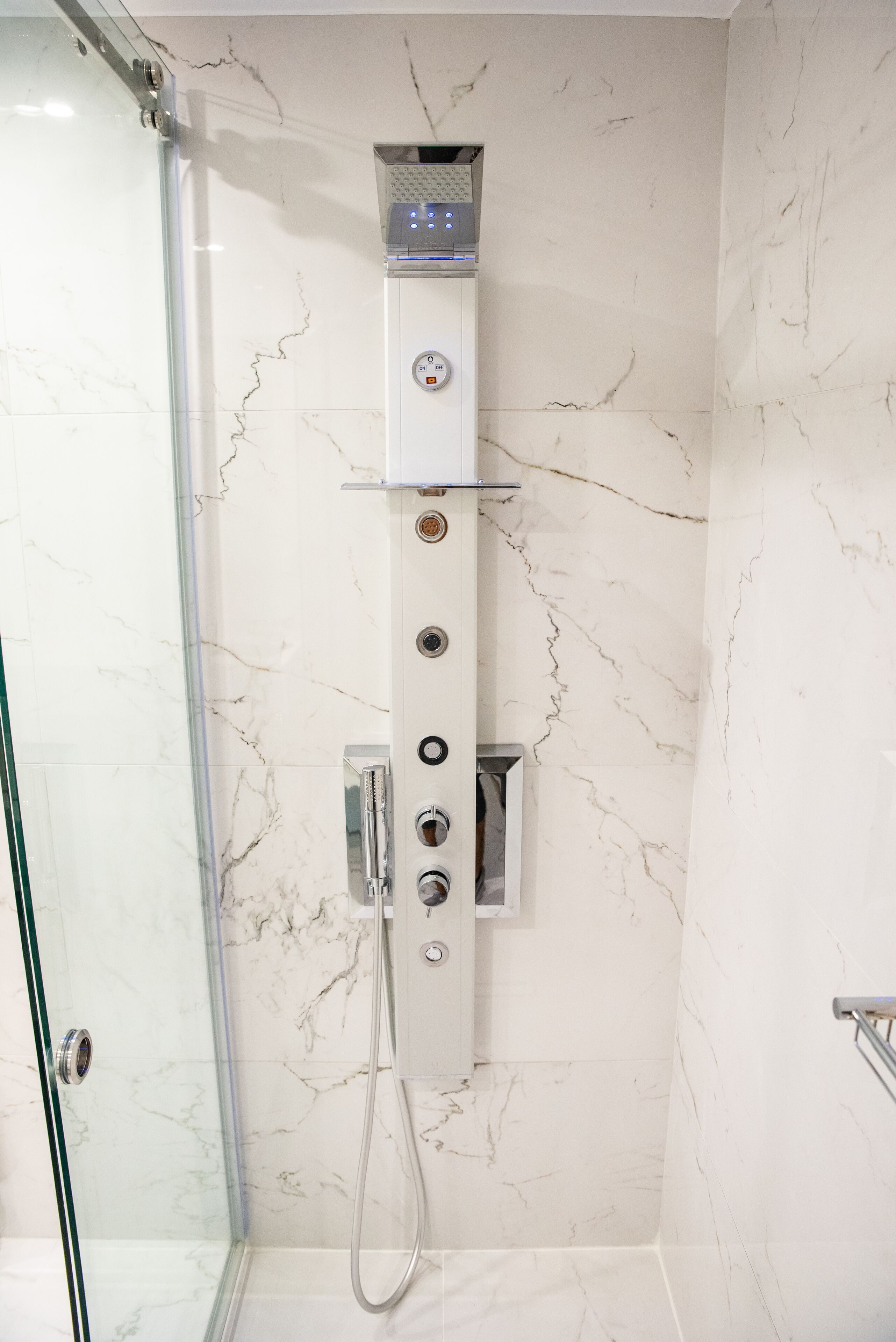A modern shower with a control panel and multiple outlets.