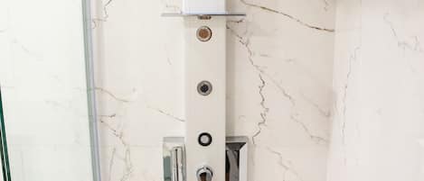 A modern shower with a control panel and multiple outlets.