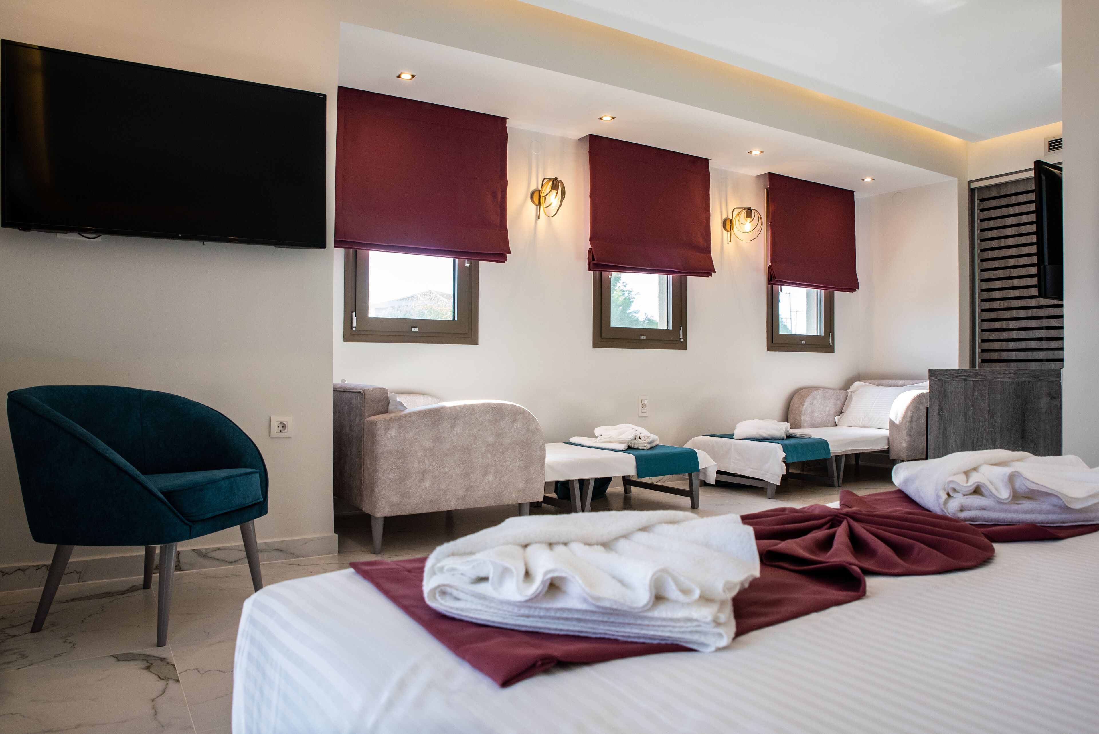 A hotel room with a bed, two chairs, a desk, and a TV.