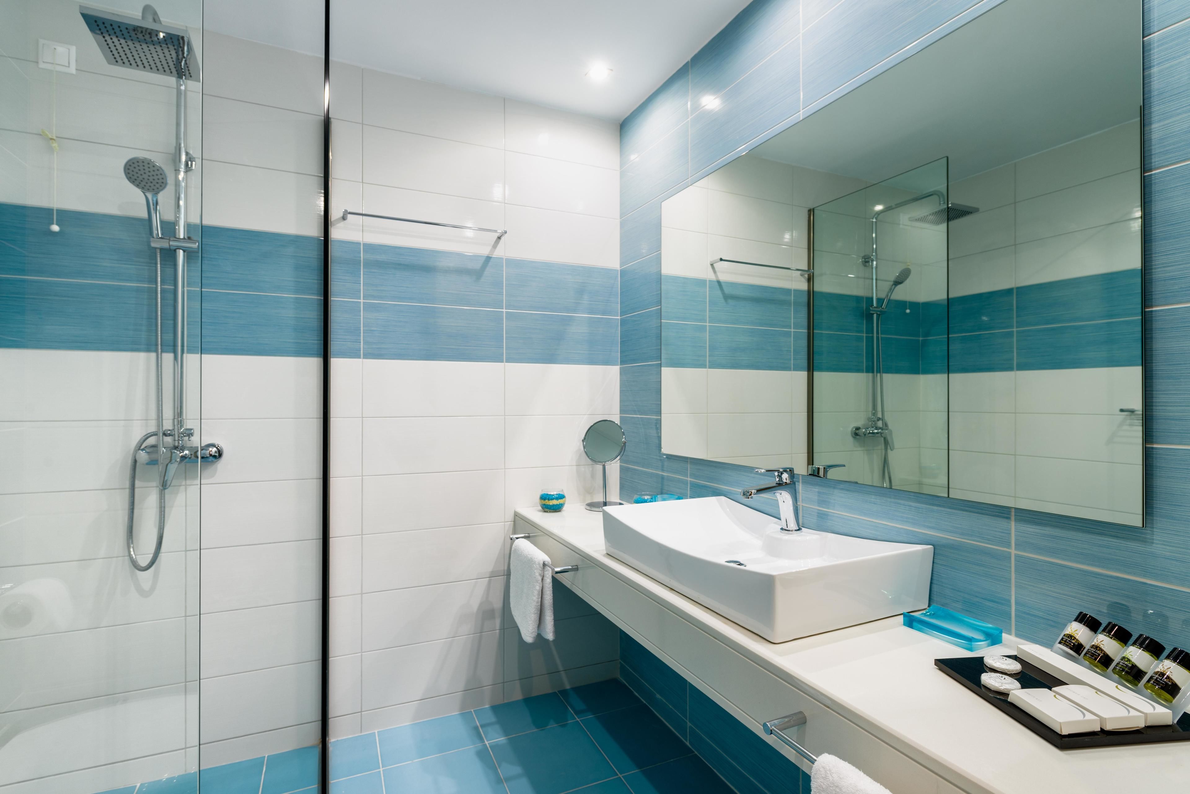 Un baño moderno con cabina de ducha de vidrio, un lavamanos blanco y un espejo grande.