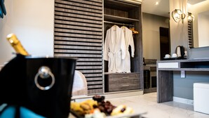 A modern bathroom with a large mirror, a wooden vanity, and a robe rack with white robes. - Lagaria Hotel (Kassandra)