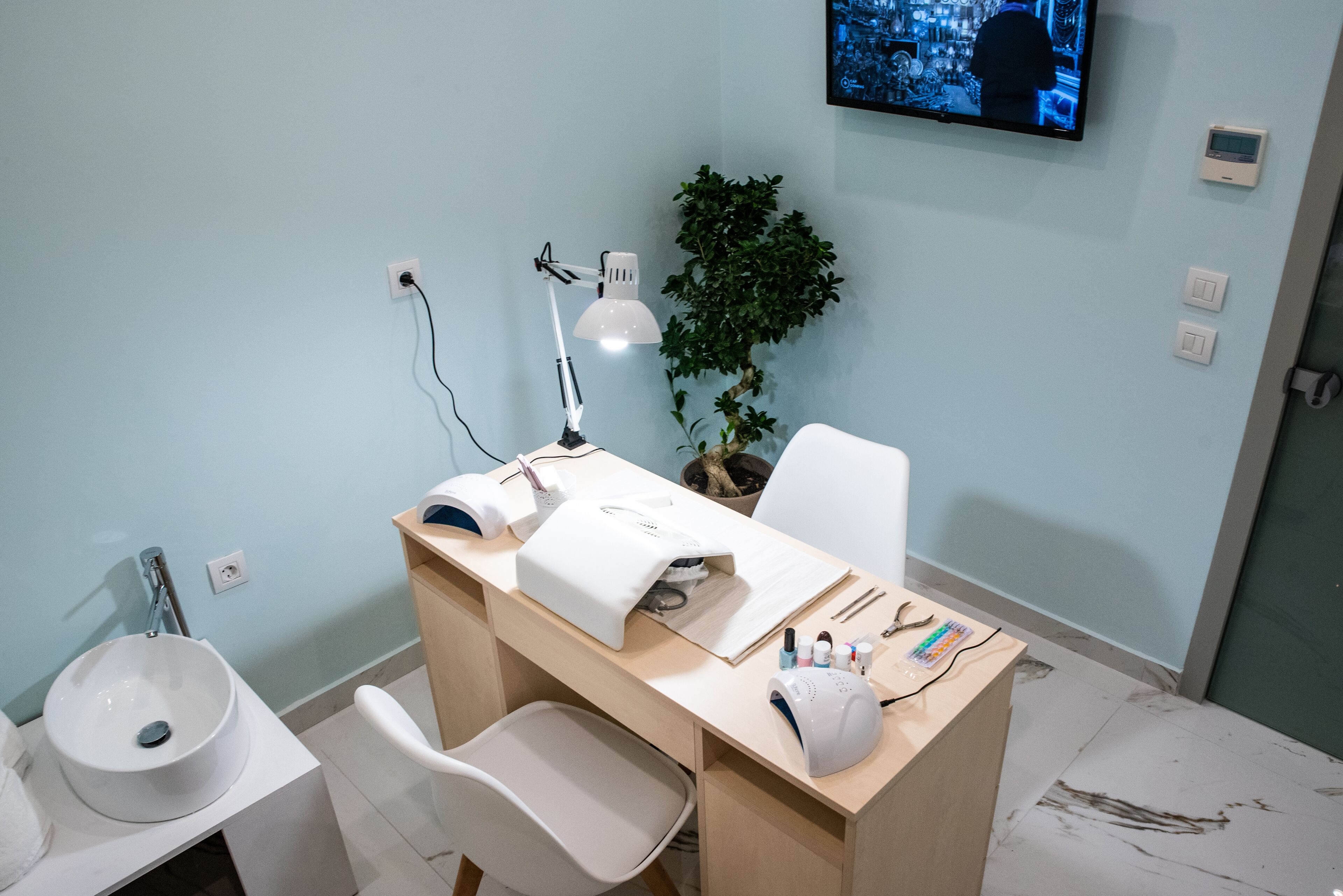 Una habitación moderna y bien iluminada con un lavamanos amplio, un escritorio con una computadora, una silla y una planta en maceta.