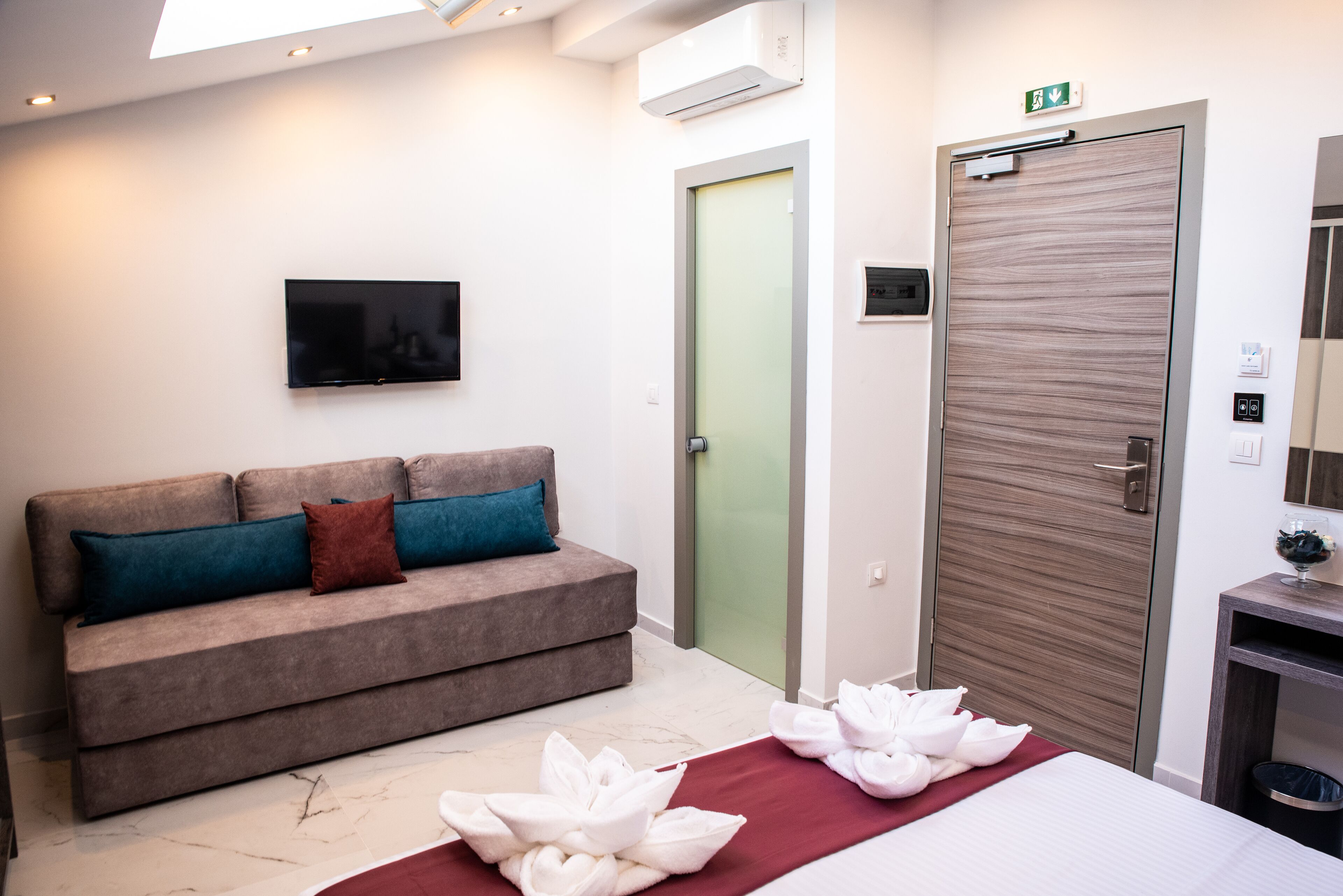 Ein Hotelzimmer mit einer Couch, einem Bett, einem Fernseher, einer Tür und einem Mülleimer.