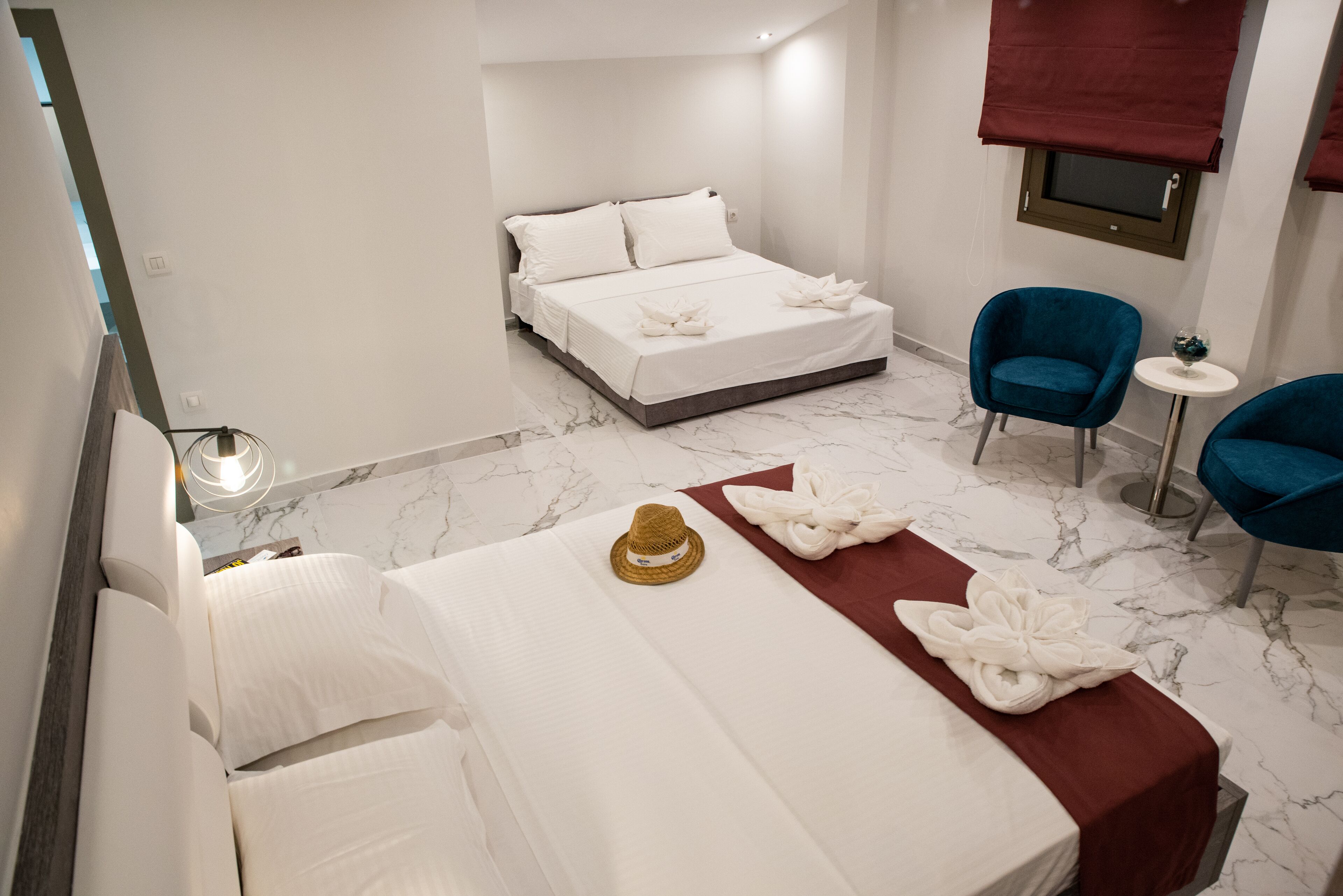 A hotel room with a bed, two chairs, a small table, and a window with a blind.
