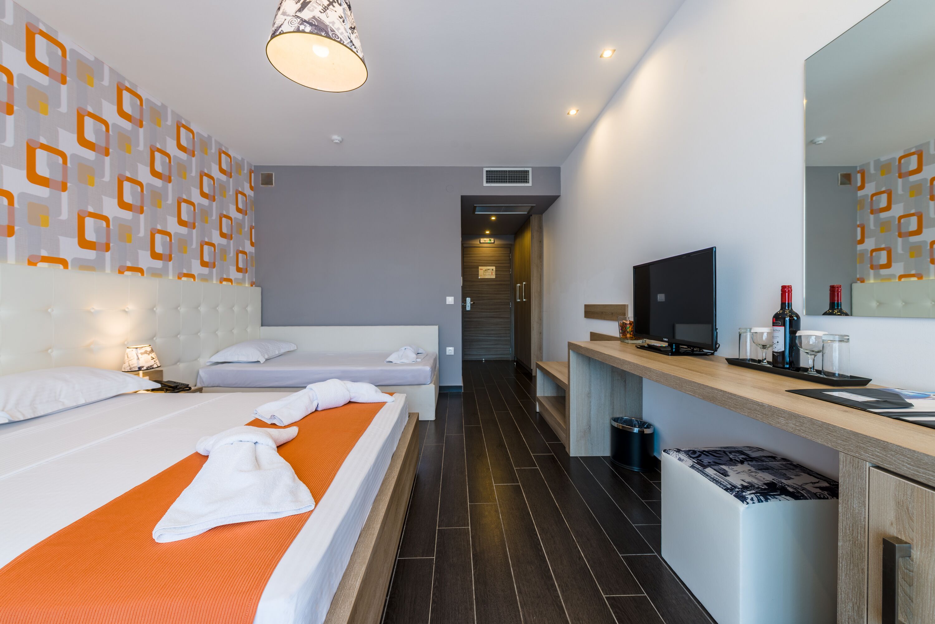 Hotellihuone, jossa on kaksi sänkyä, televisio, työpöytä ja kylpyhuone.
