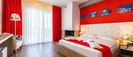 Una habitación de hotel moderna con una cama grande, un escritorio y una pared de acento roja.