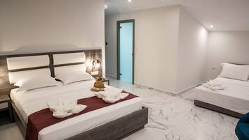 A modern hotel room with a large bed, a smaller bed, and a bathroom visible through an open door.