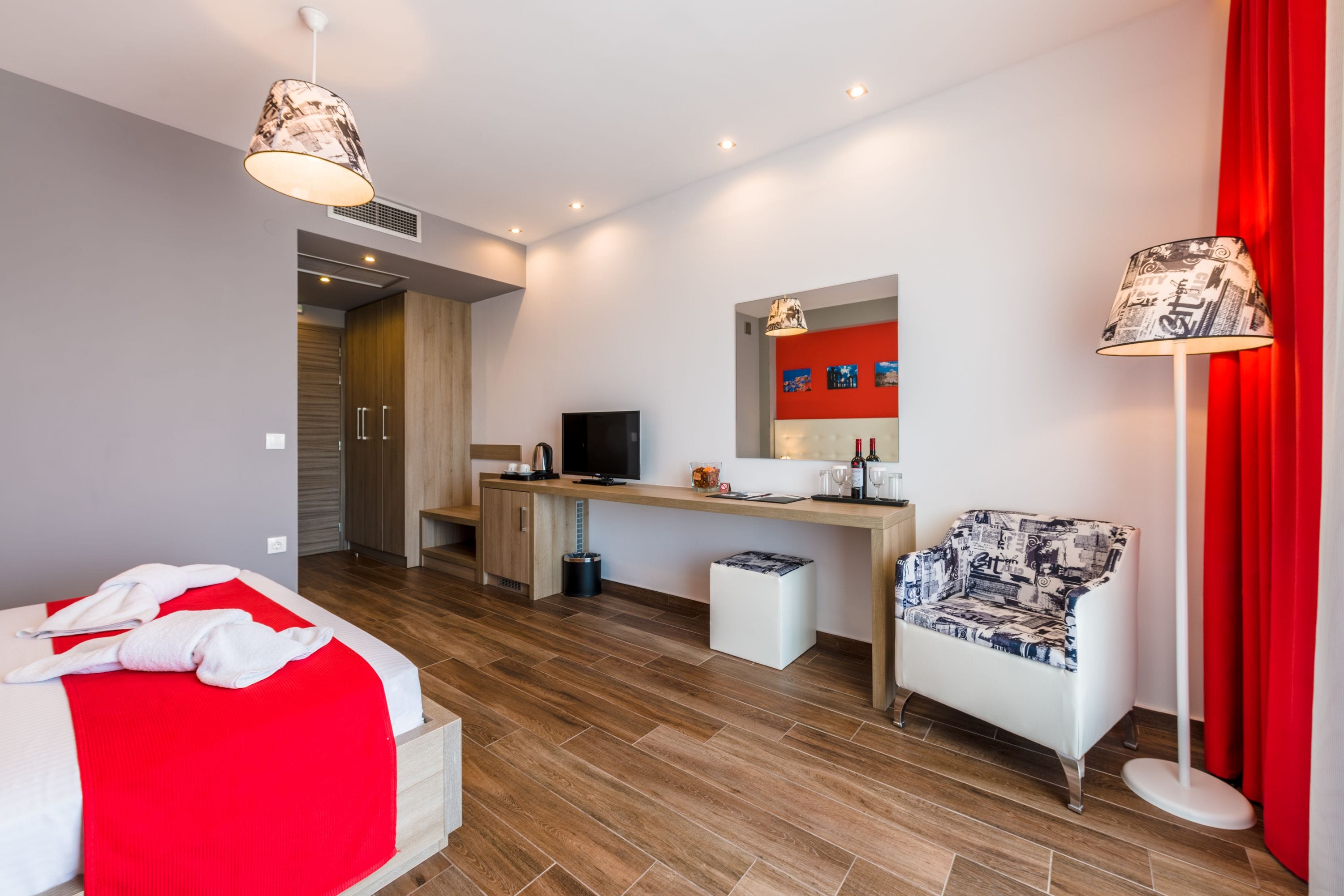 Une chambre d’hôtel moderne équipée d’un lit, d’un bureau, d’une chaise et d’un téléviseur.
