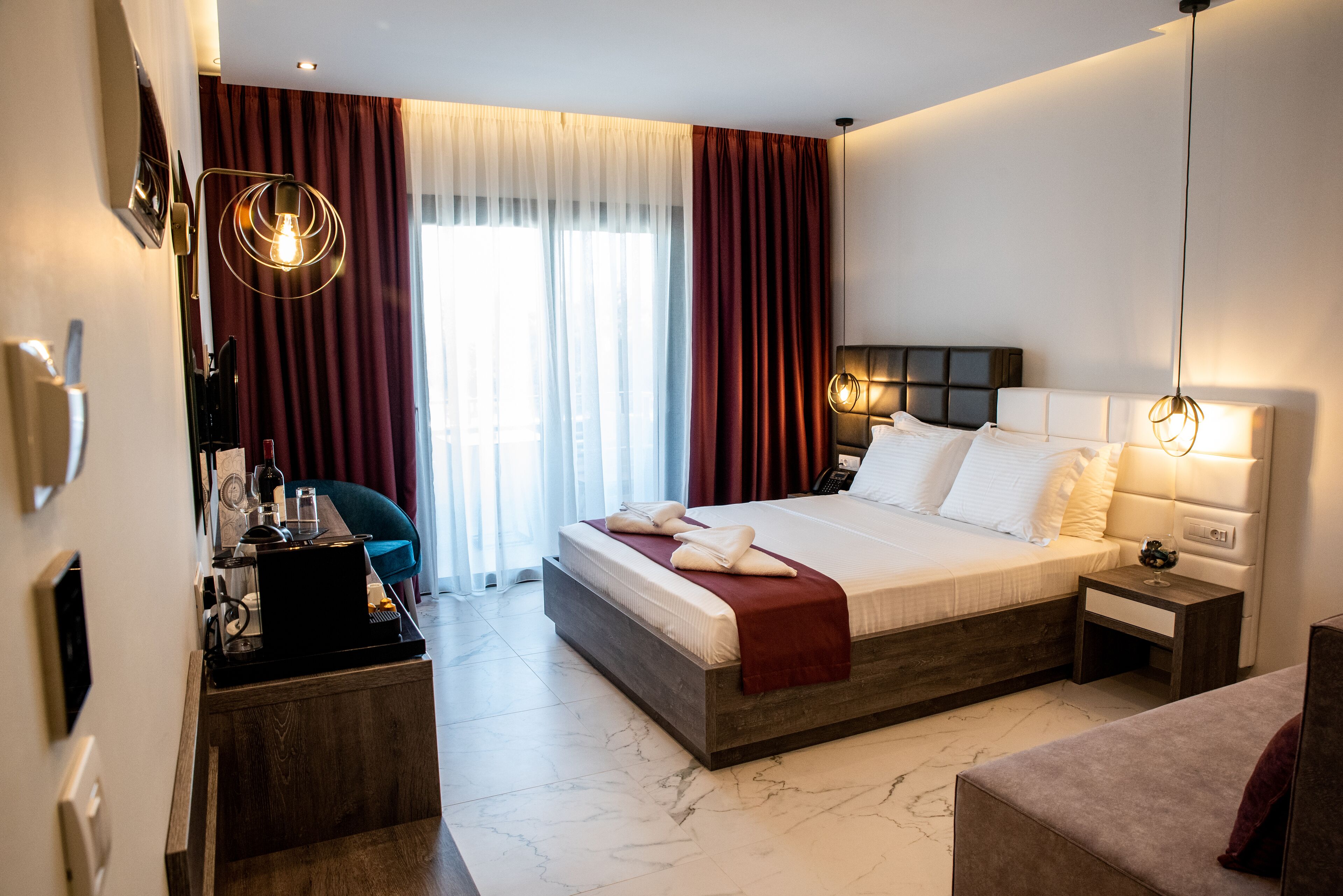 A modern hotel room with a large bed, bedside tables, a desk with a computer, and a chair.