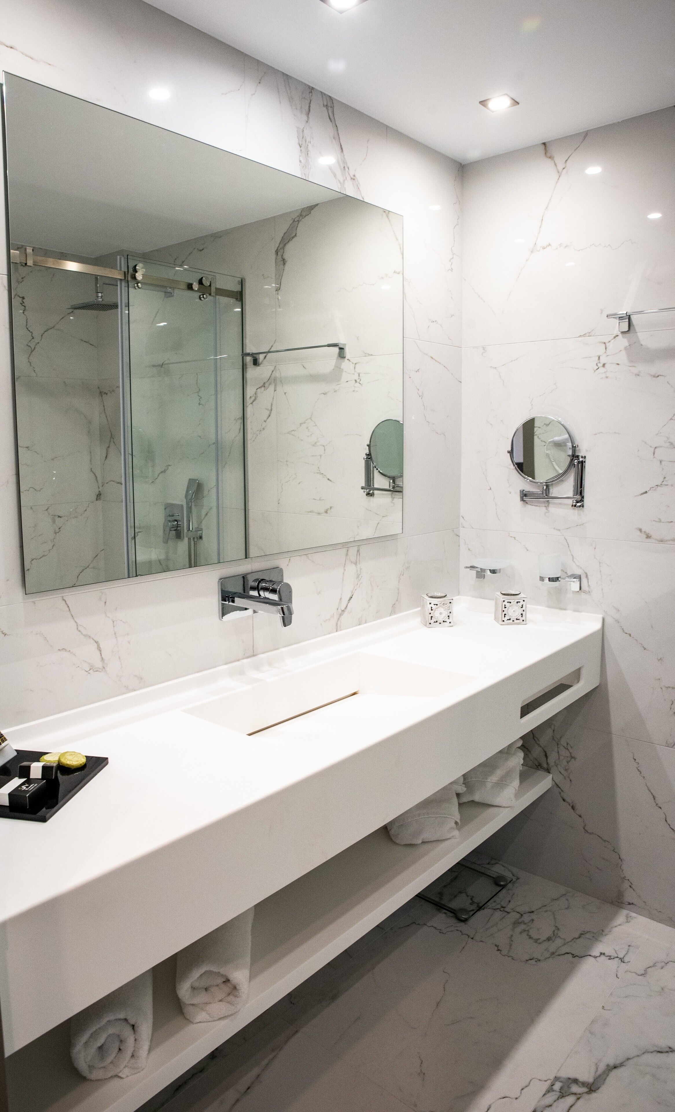 Un baño moderno con un espejo grande, dos lavamanos y una zona de ducha.