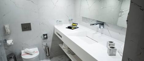A modern bathroom with a white marble sink, a large mirror, and a toilet.