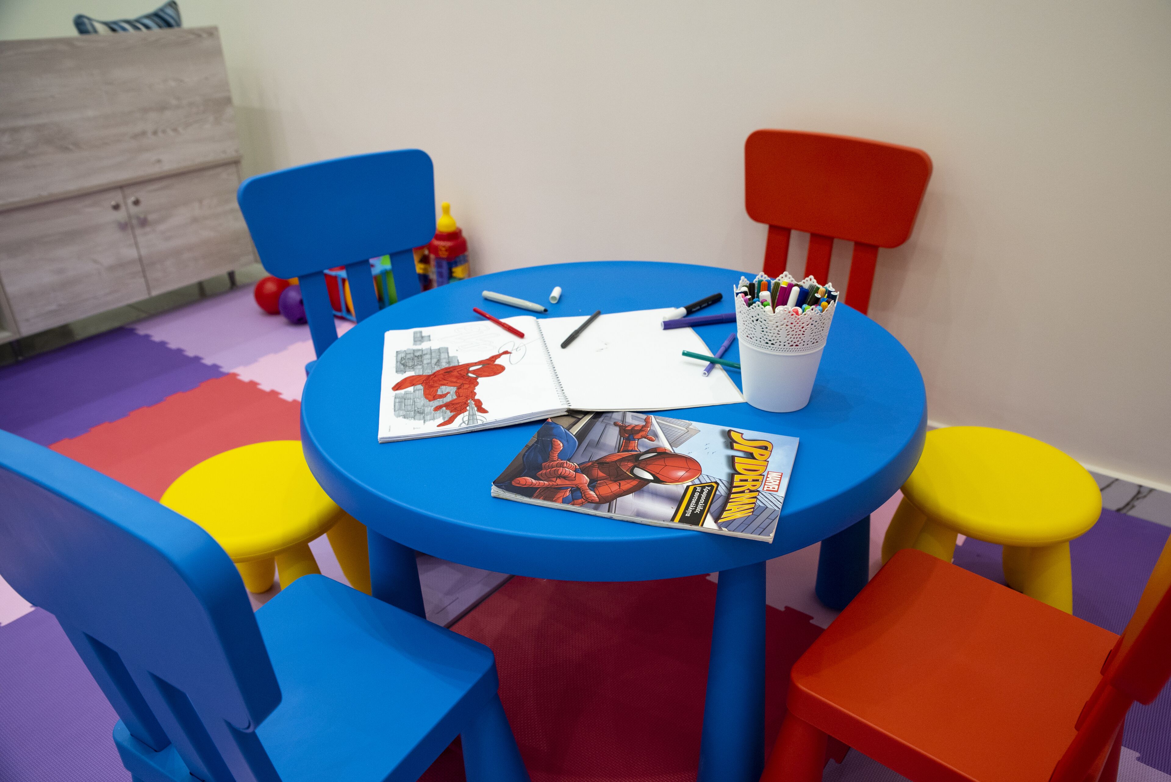 A children's table with a Spider-Man comic book, markers, and a notebook.
