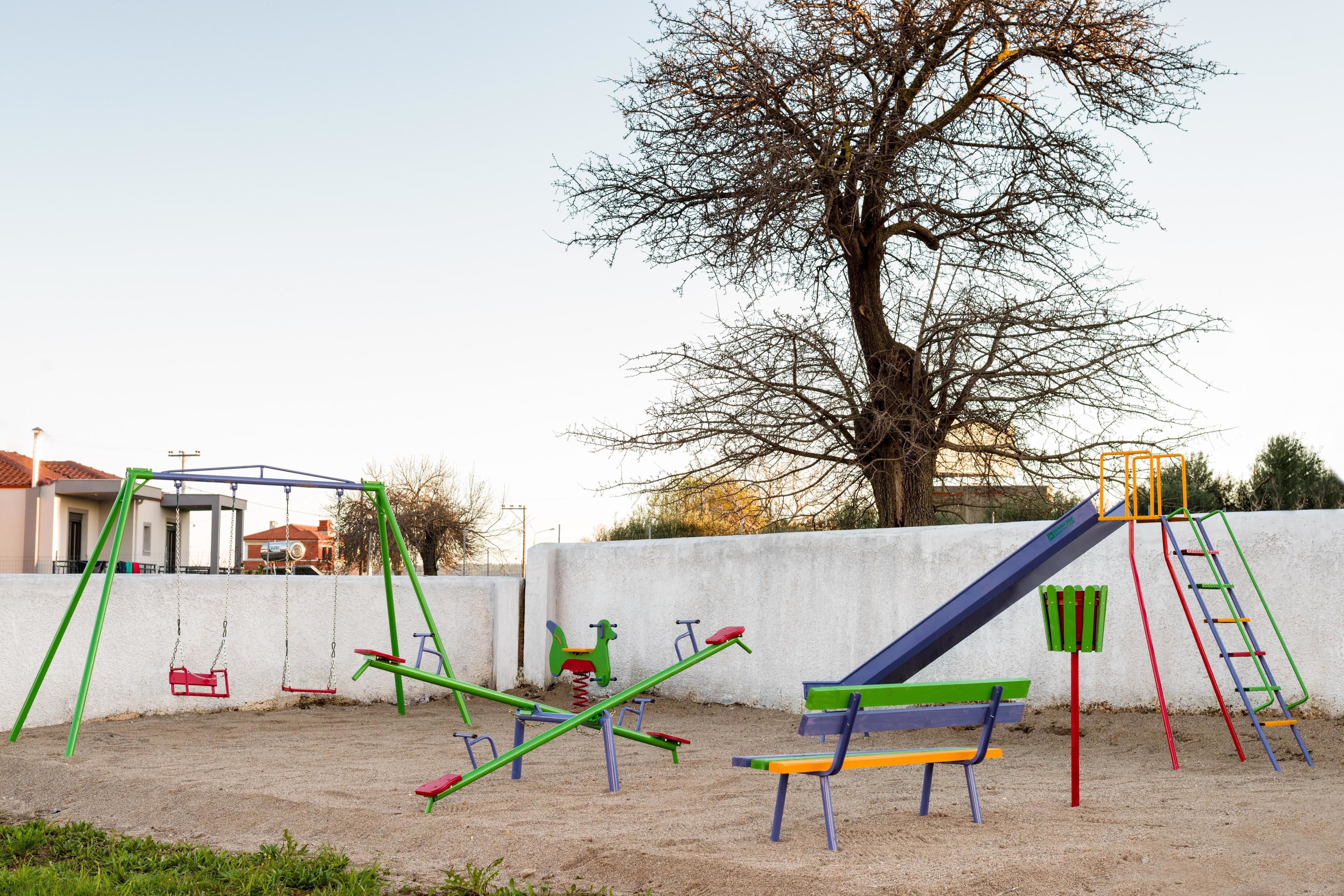 A playground with swings, seesaws, and a slide.