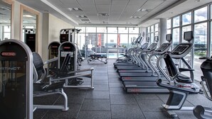 A gym with treadmills, weight machines, and a large window offering a view of the city. - Hampton Inn & Suites Richmond - Downtown (Richmond)