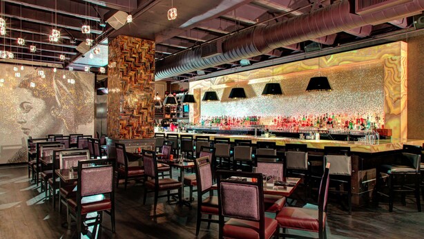 A restaurant with a bar area, multiple tables and chairs, and a decorative wall with a patterned design. - Hampton Inn & Suites Richmond - Downtown (Richmond)