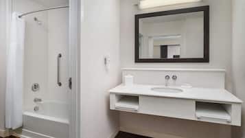 A modern bathroom with a walk-in shower, a white sink, and a large mirror.