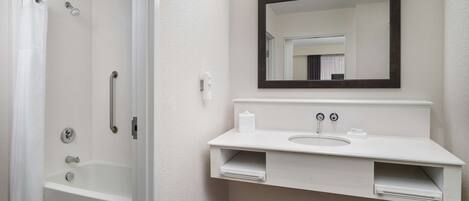 A modern bathroom with a walk-in shower, a white sink, and a large mirror.