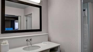 A bathroom with a large mirror, a sink, and a shower area.