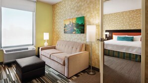 Hotelkamer met een bank, een bed, een lamp en een schilderij van een stadsgezicht.