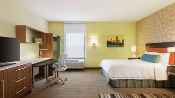 Una habitación de hotel con escritorio, silla, cama y un cuadro de paisaje urbano en la pared.
