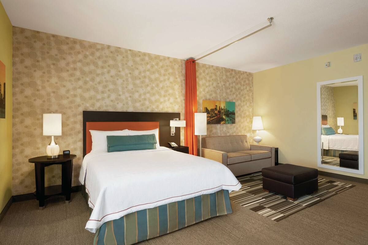 Une chambre d’hôtel avec un grand lit, un canapé, une petite table et un miroir.