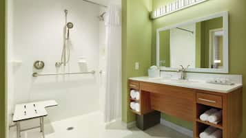 Un baño moderno con cabina de ducha, tocador con espejo y retrete.