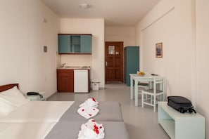 Une chambre d’hôtel compacte comprenant un lit, une petite kitchenette, une table à manger et un banc.