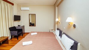 Habitación de hotel con cama doble, escritorio con silla, televisor y espejo.