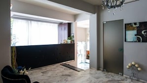 Una sala de estar moderna con un sofá oscuro, una lámpara de araña y un ventanal con cortinas.