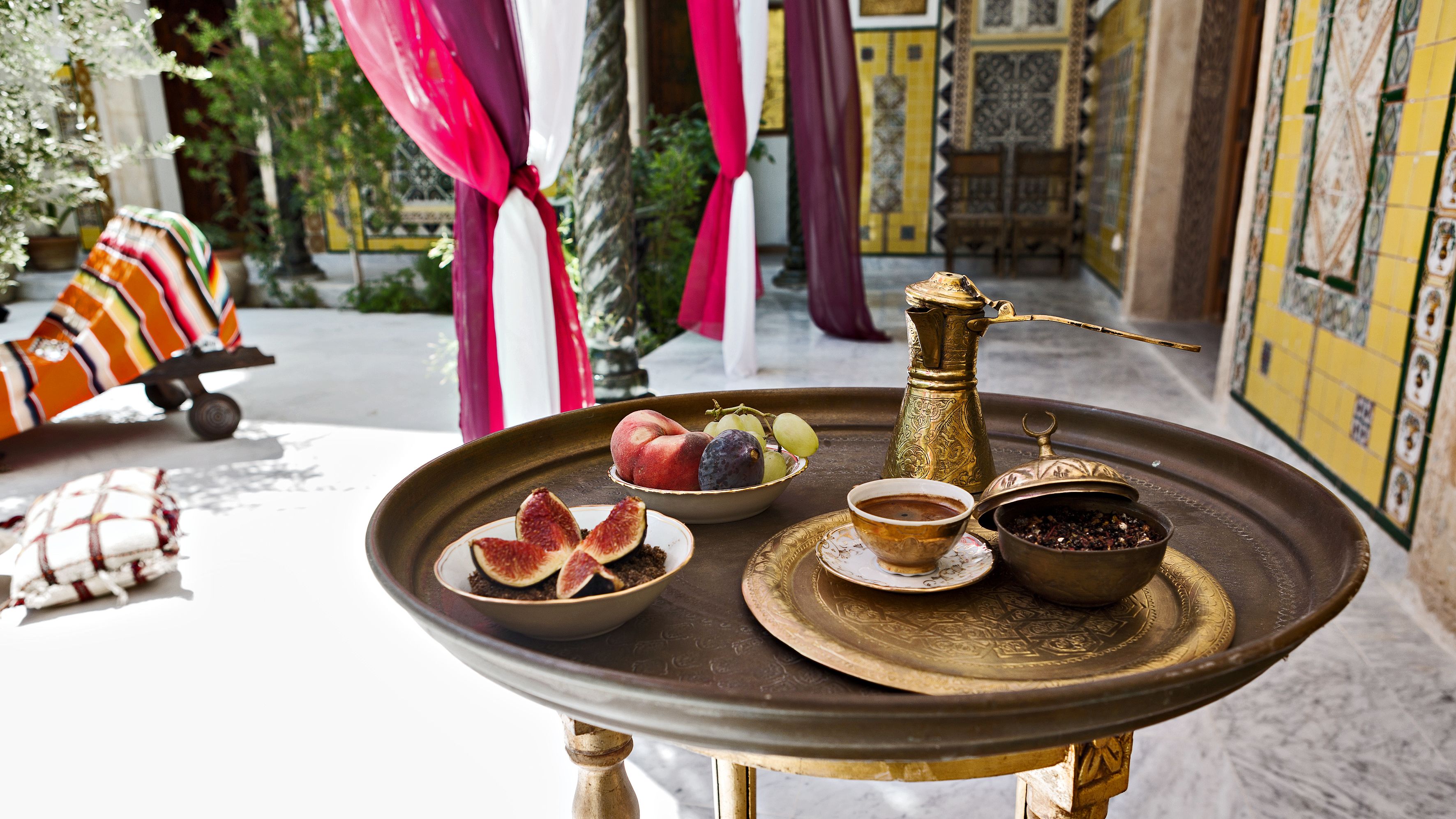 A tray with a brass coffee pot, a bowl of figs, a bowl of coffee, and a container of spices.