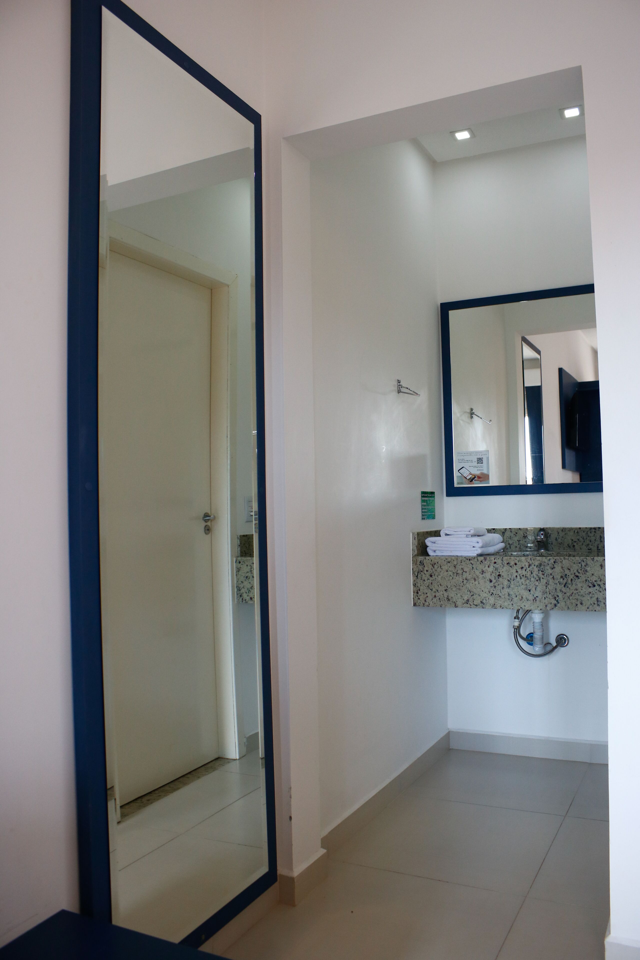 Un bagno con uno specchio grande, un lavabo con piano in granito e una porta che dà su un'altra stanza.