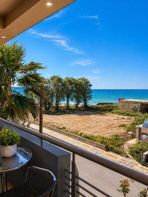 Ein Balkon mit Blick auf den Strand, ein Tisch mit einem Stuhl und ein Blumentopf.