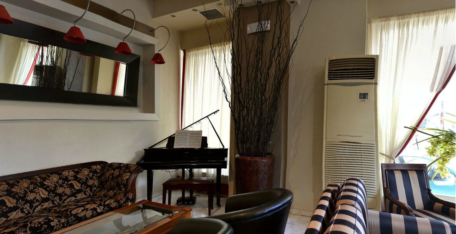 Ein Wohnzimmer mit einem Klavier, einem Sofa, einem Couchtisch und einem gestreiften Sessel.