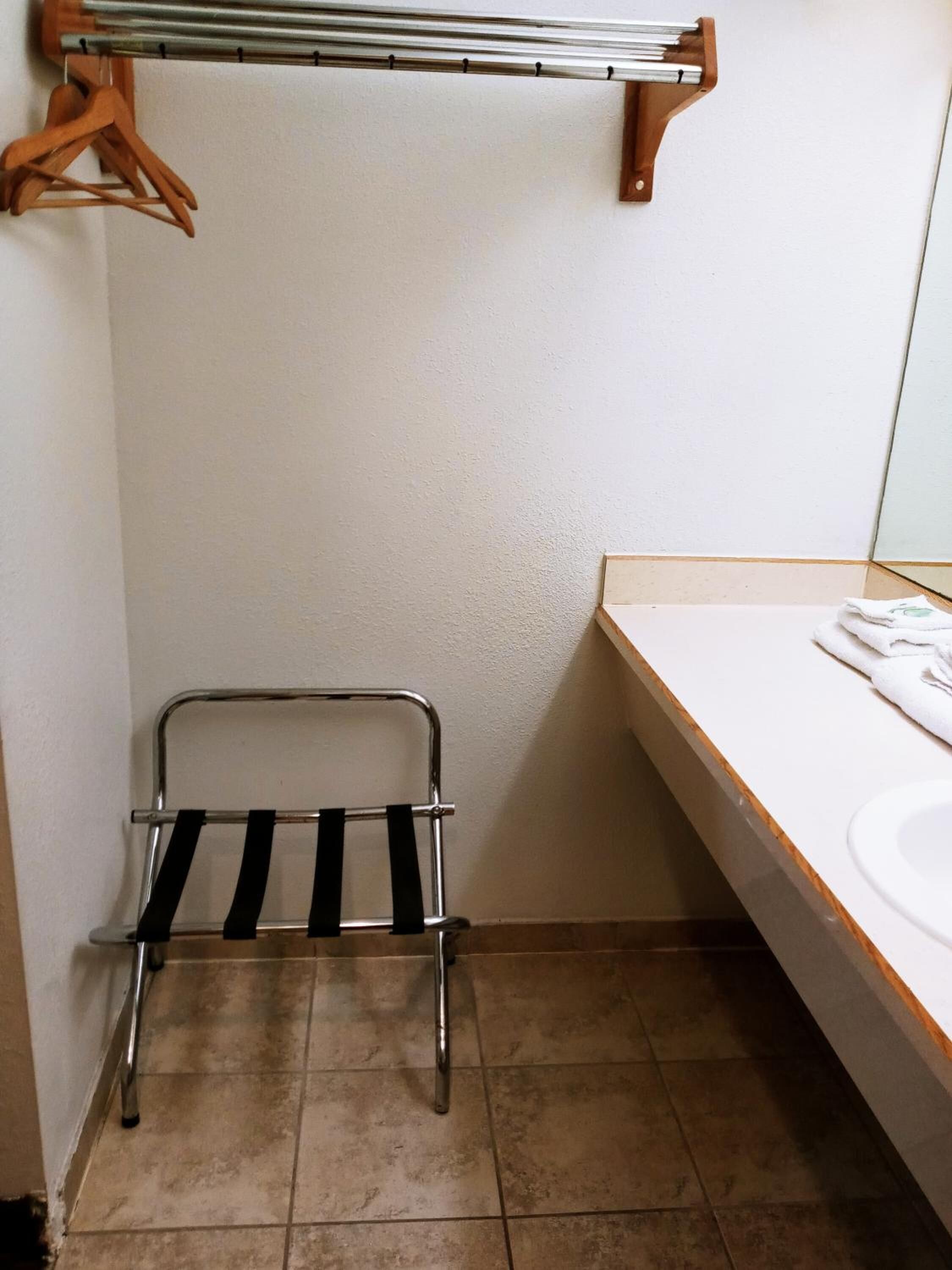 A bathroom with a towel rack, a metal drying rack, a sink, and a mirror.