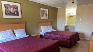 Habitación de hotel con dos camas, un cabecero de madera, una mesita de noche y un cuadro en la pared.