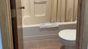 Un baño con bañera, cortina de ducha y retrete.