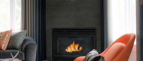 A modern living room with a fireplace, a sofa, an orange armchair, and a decorative deer head on the wall.