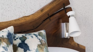 A wooden headboard with a white lamp and a bed with patterned pillows.