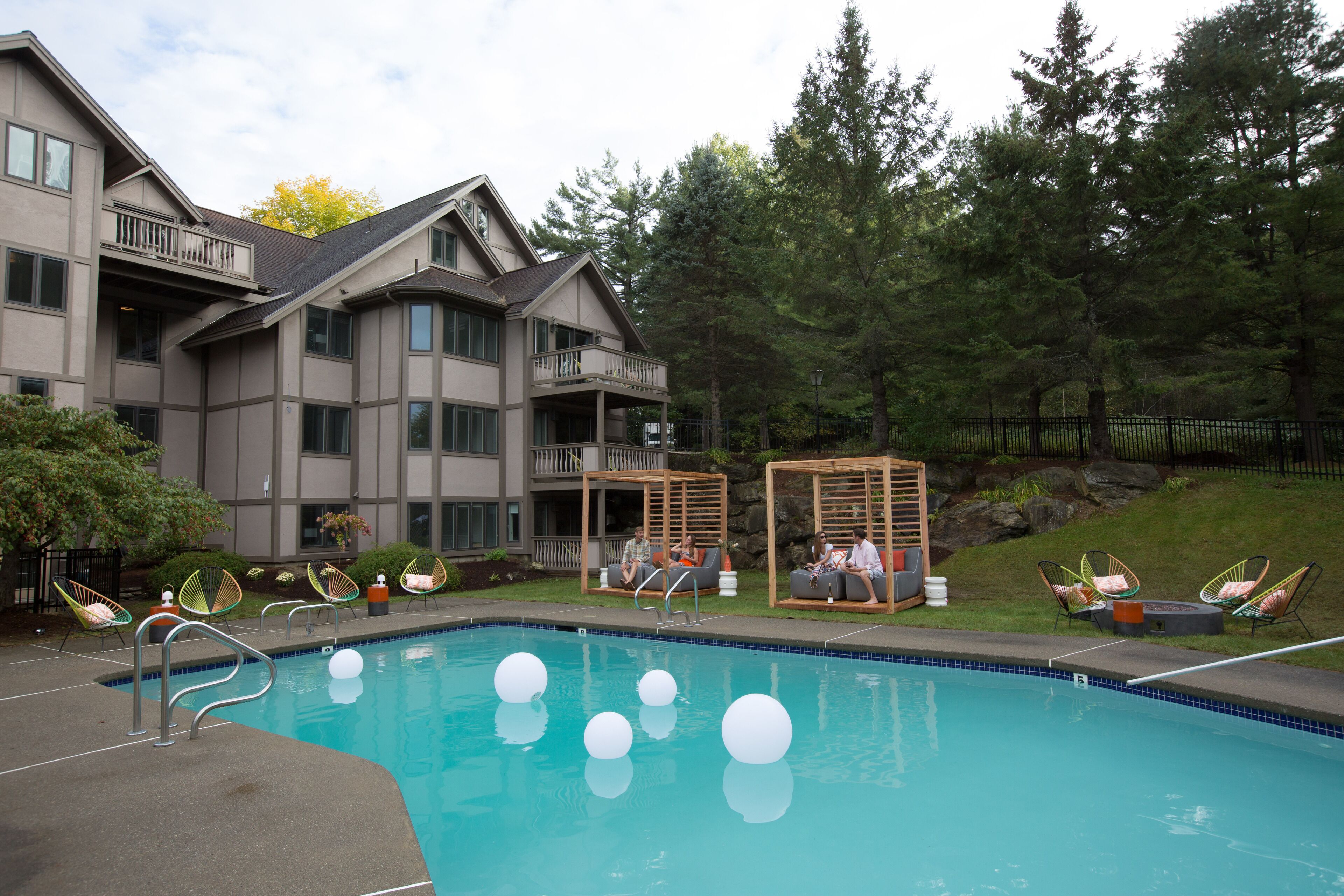A swimming pool with lounge chairs and a wooden pergola.