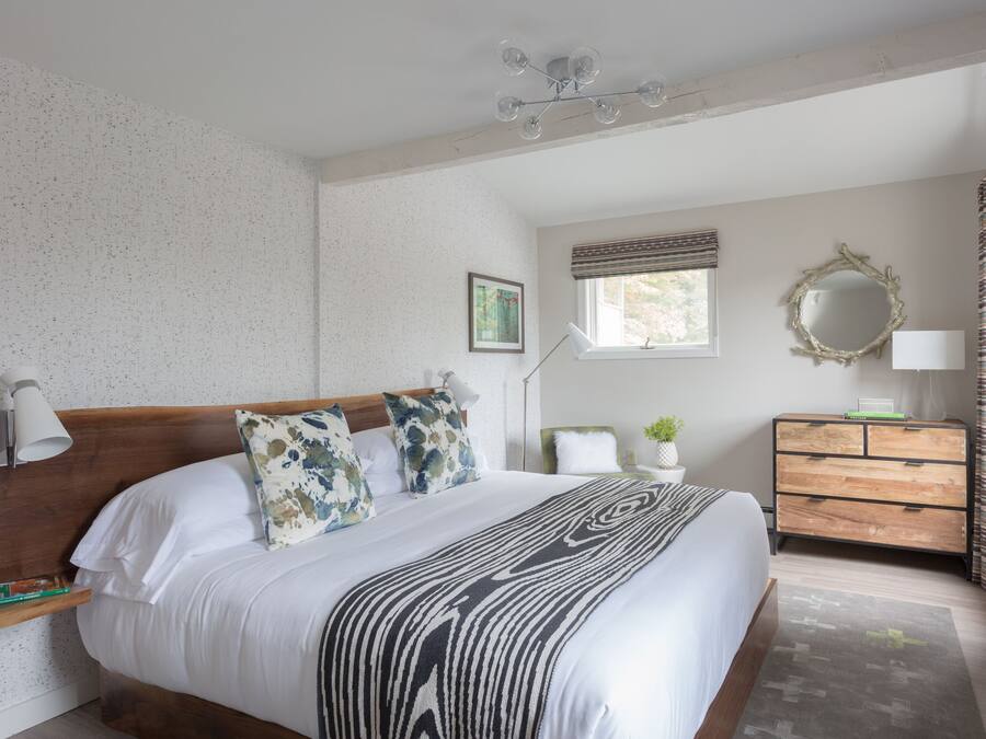 A neatly arranged bedroom with a large bed, bedside tables, a dresser, and a window with curtains.