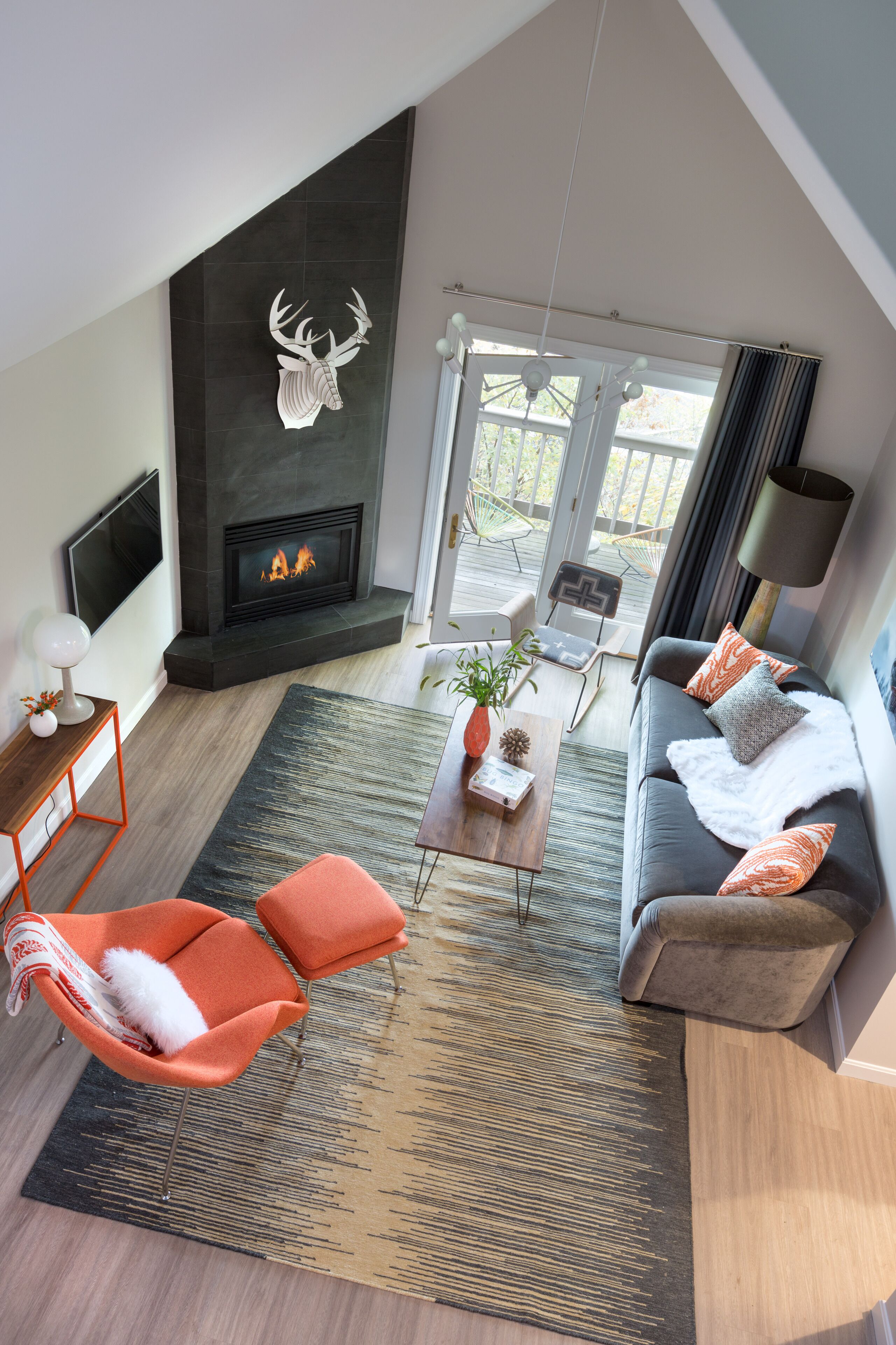 A modern living room with a fireplace, a sofa, a coffee table, and orange chairs.