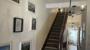 A staircase with leopard print steps, framed pictures on the walls, and a chandelier. - Hotel Jägerhof Kettwig (Essen)
