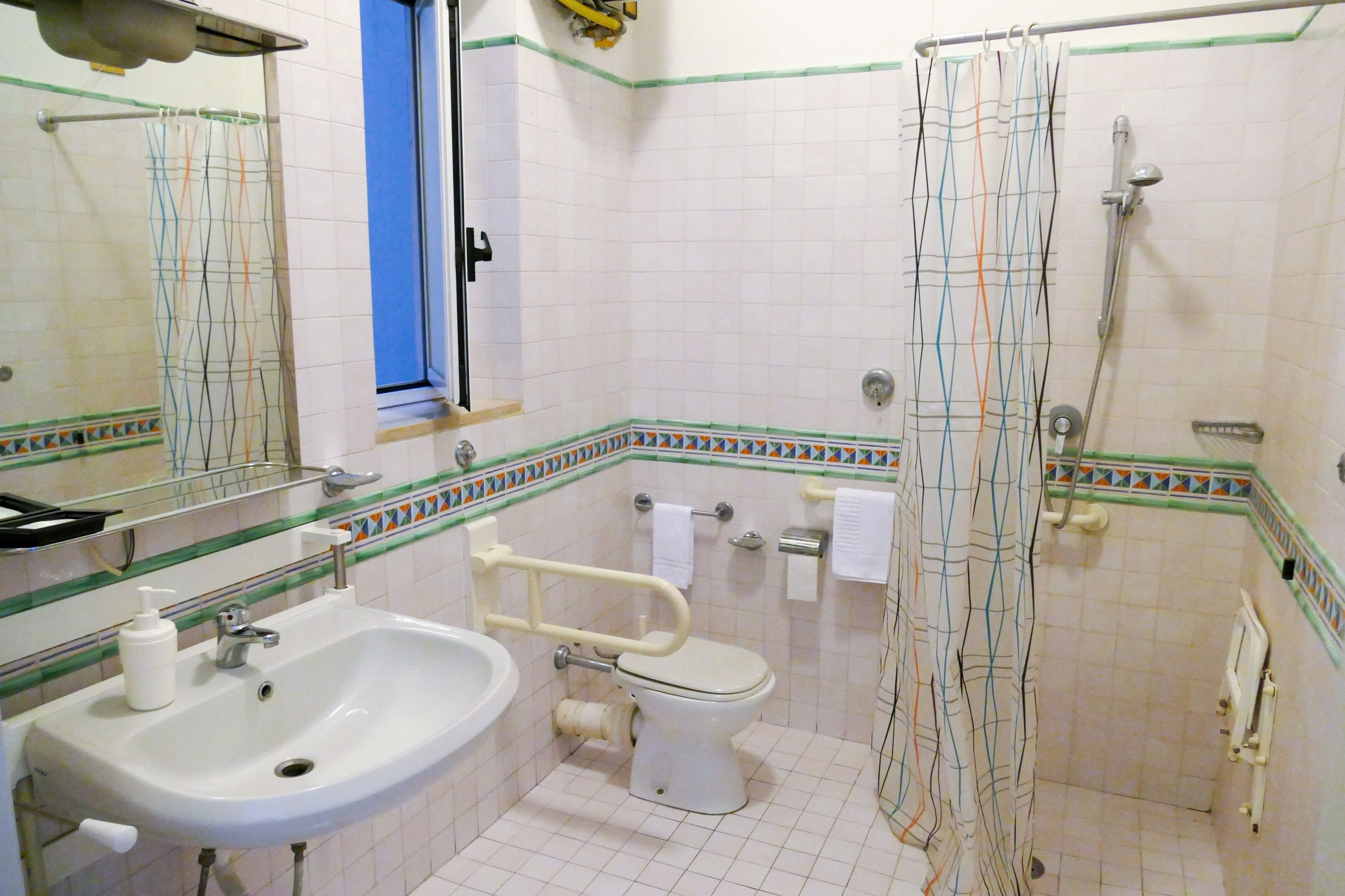 Une salle de bain avec un lavabo, des toilettes et une douche, le tout de couleur blanche.