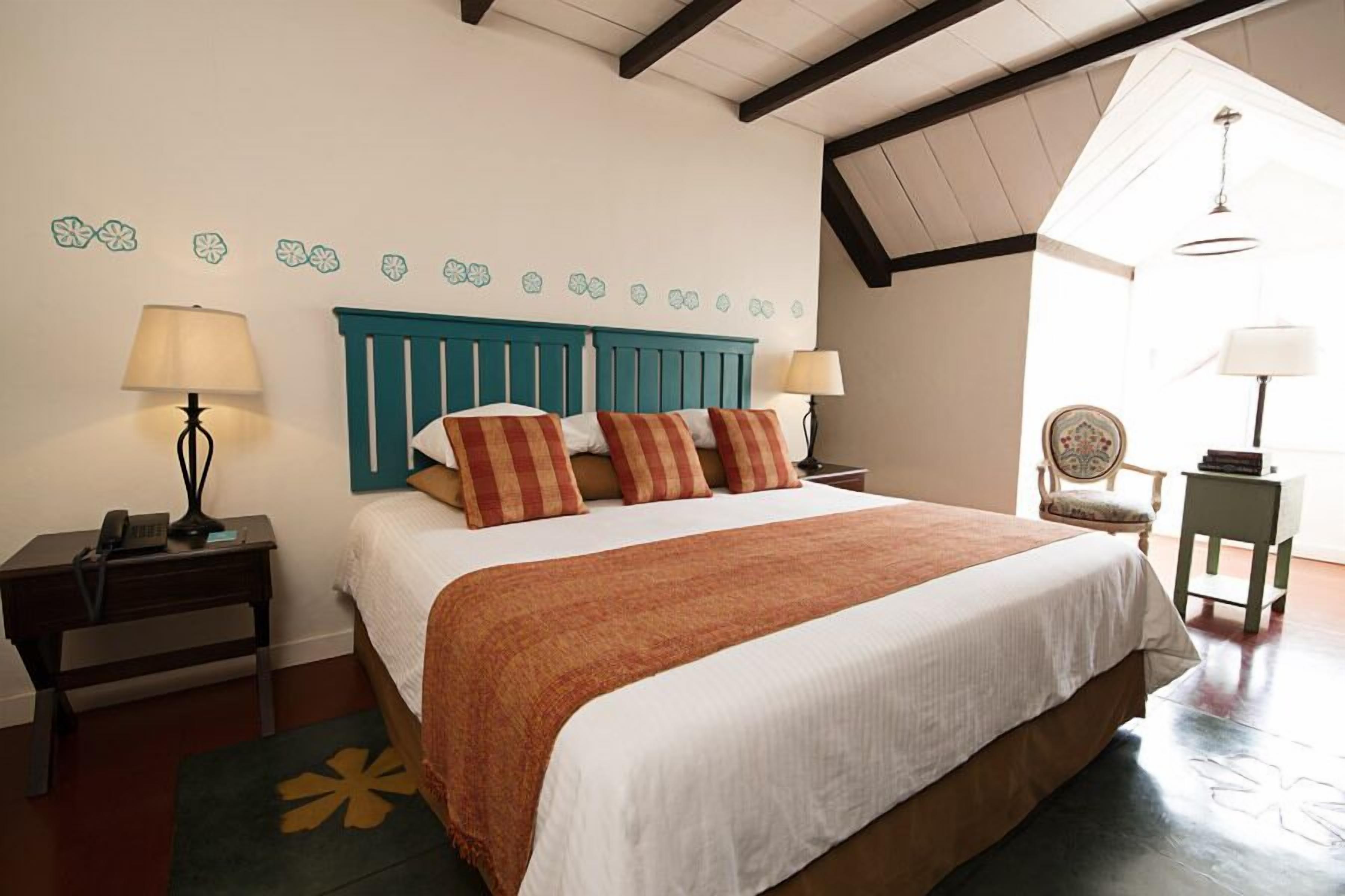 A bedroom with a large bed, two bedside tables, a chair, and a small table with a lamp.