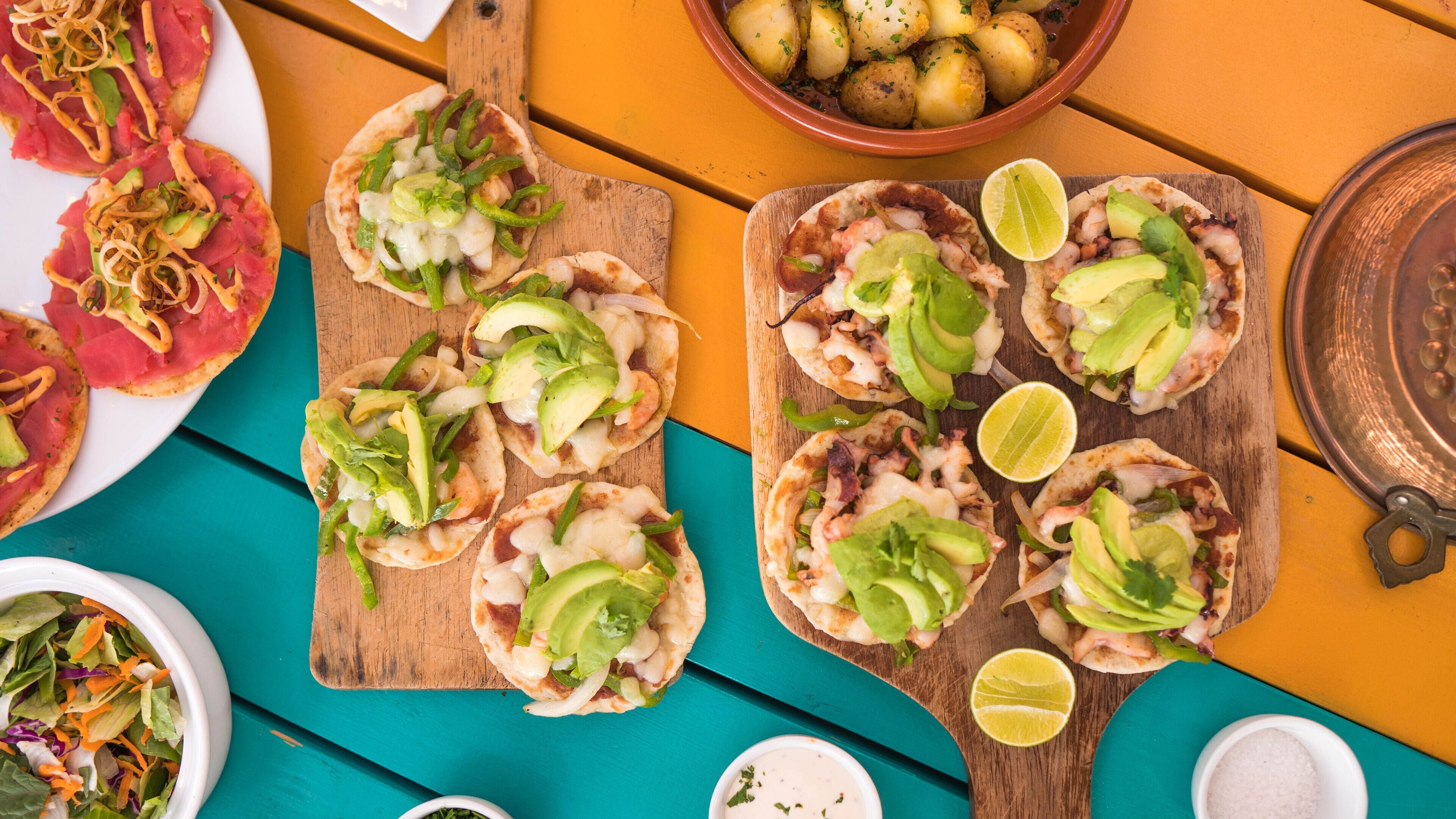 A table with various dishes including tacos, a bowl of potatoes, and a bowl of salad.